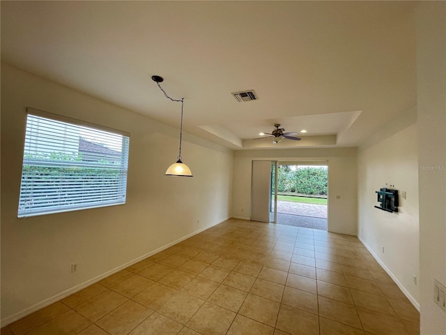 tiled empty room featuring a tray ceiling and ceiling fan