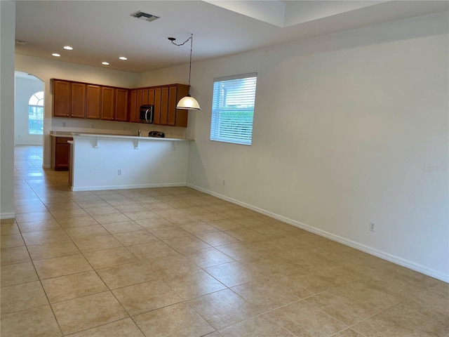 kitchen featuring a healthy amount of sunlight, a breakfast bar area, kitchen peninsula, and hanging light fixtures