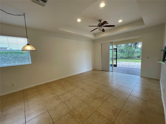 empty room featuring light tile patterned floors, a tray ceiling, and ceiling fan