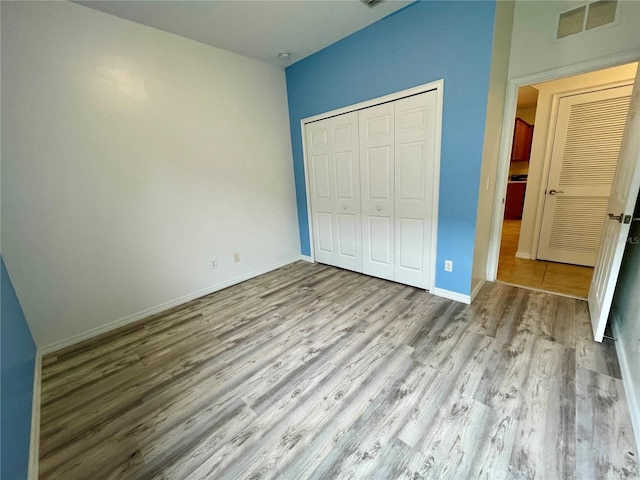 unfurnished bedroom featuring light hardwood / wood-style floors and a closet