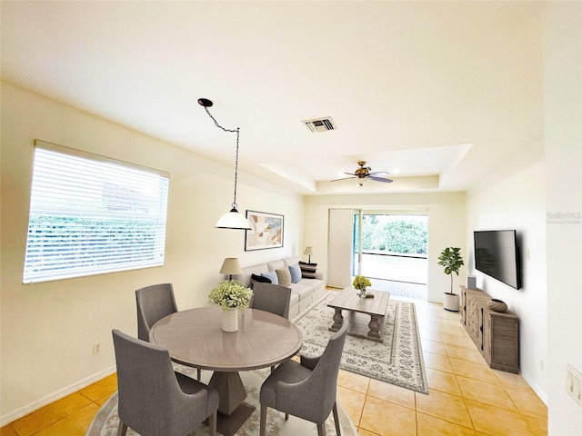 tiled dining room with a raised ceiling and ceiling fan