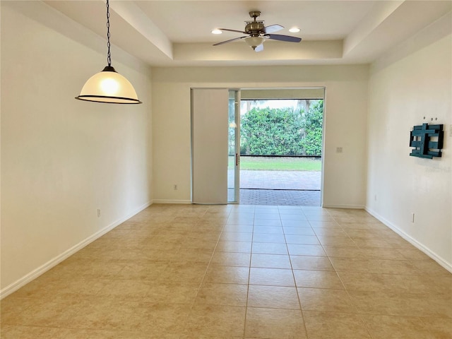 unfurnished room featuring light tile patterned floors, ceiling fan, and a tray ceiling