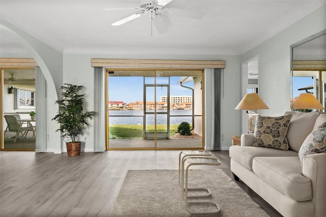 living room with hardwood / wood-style flooring, ceiling fan, and a water view