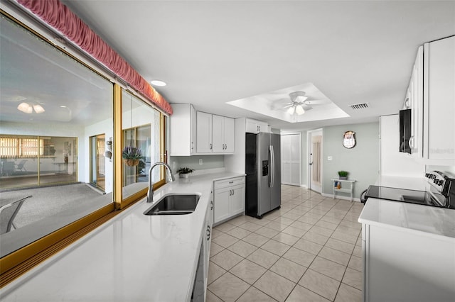 kitchen featuring white cabinets, electric stove, sink, a tray ceiling, and stainless steel fridge with ice dispenser