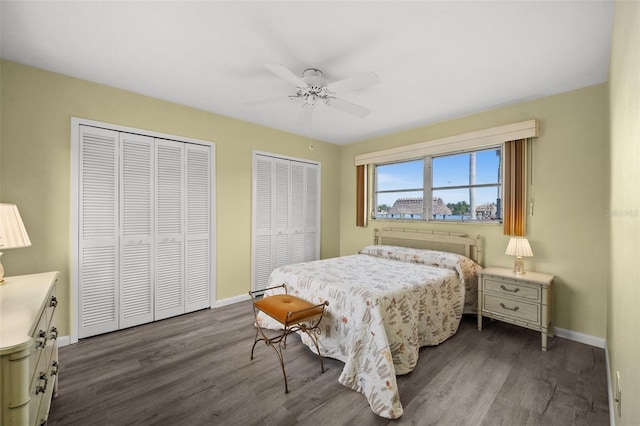 bedroom with dark wood-type flooring, ceiling fan, and multiple closets