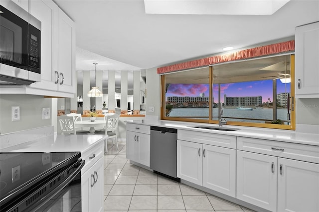 kitchen with pendant lighting, sink, light tile patterned floors, appliances with stainless steel finishes, and white cabinetry