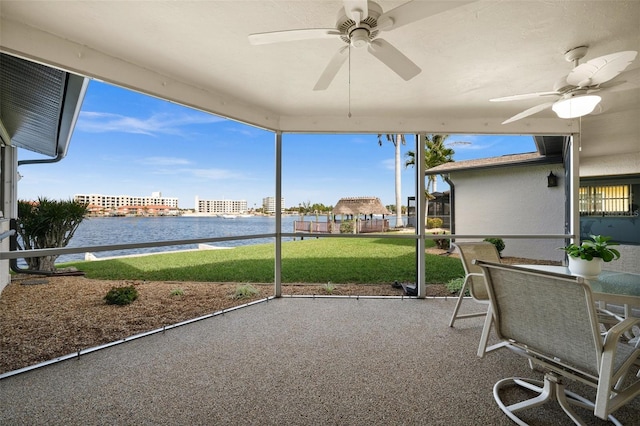 unfurnished sunroom with ceiling fan, a water view, and plenty of natural light