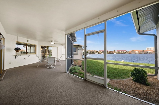 unfurnished sunroom featuring ceiling fan and a water view