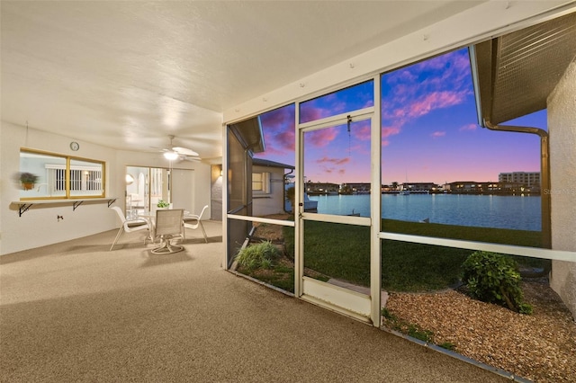 unfurnished sunroom with a water view and ceiling fan