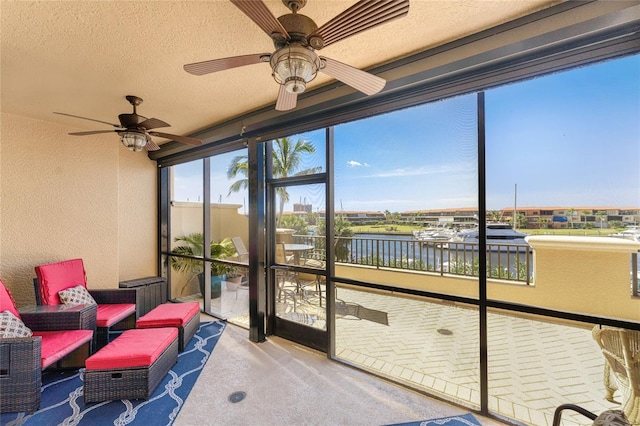 sunroom / solarium with ceiling fan and a water view