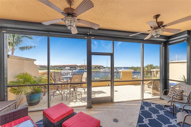 sunroom / solarium featuring a ceiling fan and a water view