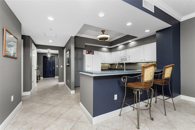 kitchen featuring a breakfast bar, ornamental molding, white cabinets, white appliances, and a peninsula