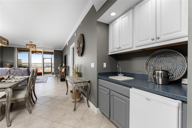 kitchen featuring dark countertops, white cabinetry, white dishwasher, and a sink