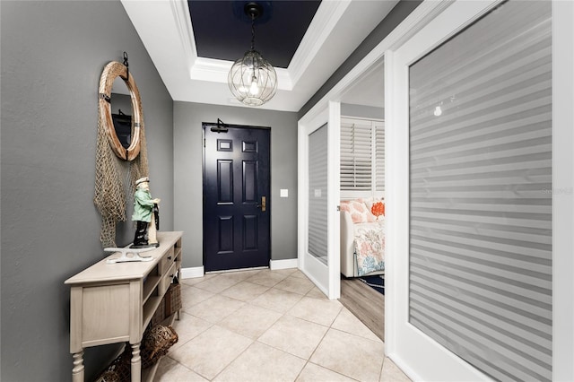 entryway featuring light tile patterned floors, baseboards, a tray ceiling, crown molding, and a chandelier