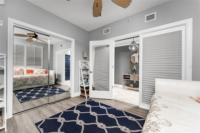 bedroom with baseboards, ceiling fan, visible vents, and wood finished floors