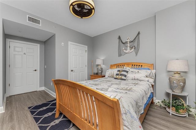 bedroom featuring visible vents, baseboards, and wood finished floors