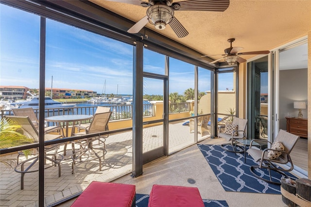 sunroom featuring a water view, a healthy amount of sunlight, and ceiling fan