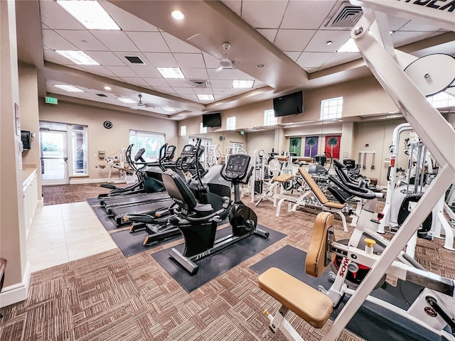 exercise room with a wealth of natural light, a towering ceiling, and visible vents