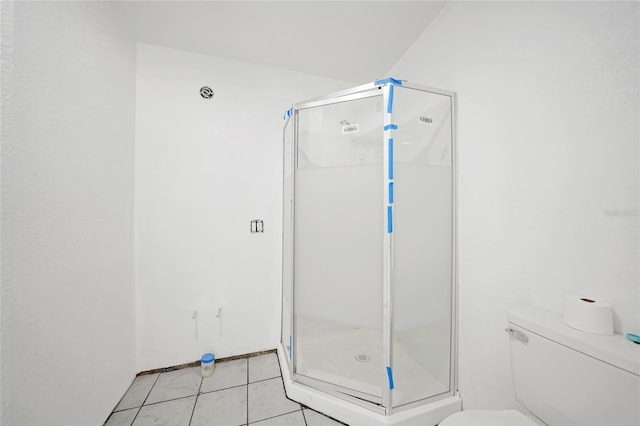 bathroom featuring tile patterned floors, a shower with door, and toilet