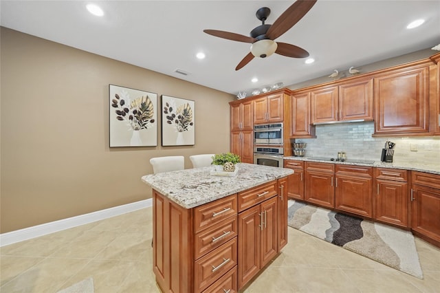 kitchen featuring a center island, stainless steel oven, black electric stovetop, decorative backsplash, and light stone counters