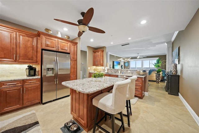 kitchen featuring stainless steel fridge with ice dispenser, a center island, tasteful backsplash, and a breakfast bar area