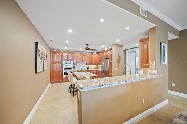 kitchen featuring kitchen peninsula, light stone countertops, ornamental molding, stainless steel appliances, and ceiling fan