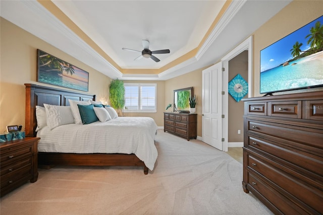 bedroom featuring ceiling fan, a raised ceiling, light colored carpet, and ornamental molding