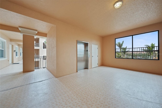 unfurnished room with elevator and a textured ceiling