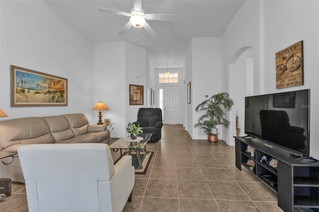 living room with ceiling fan, a towering ceiling, and tile patterned floors