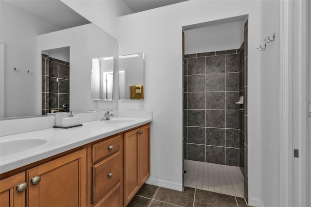 bathroom with tile patterned flooring, a tile shower, and vanity