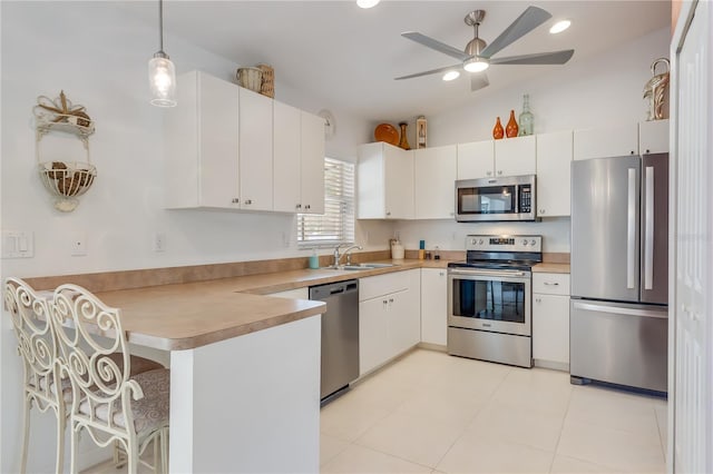 kitchen with white cabinetry, sink, hanging light fixtures, stainless steel appliances, and kitchen peninsula