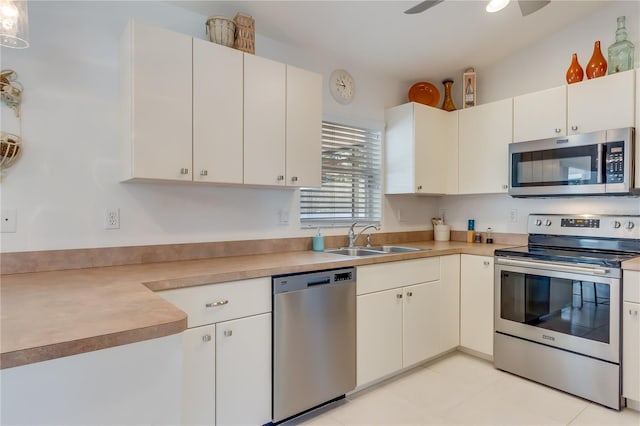 kitchen featuring ceiling fan, sink, stainless steel appliances, light tile patterned floors, and white cabinets