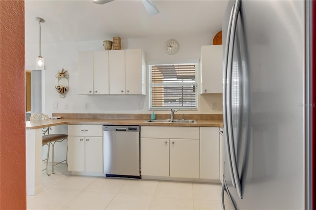 kitchen with appliances with stainless steel finishes, white cabinetry, pendant lighting, and sink