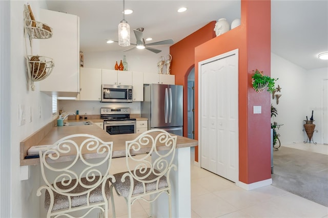 kitchen with kitchen peninsula, appliances with stainless steel finishes, ceiling fan, sink, and light tile patterned floors