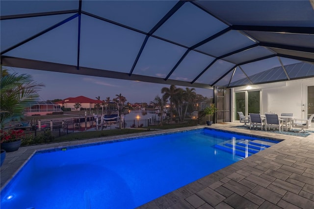 pool at dusk featuring a lanai and a patio