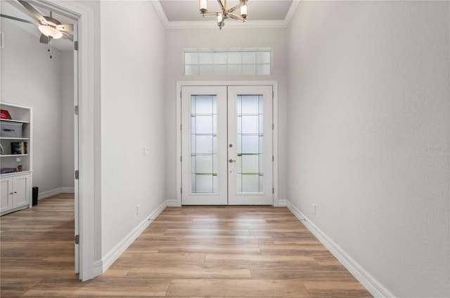 doorway with french doors, ornamental molding, an inviting chandelier, and light wood-type flooring