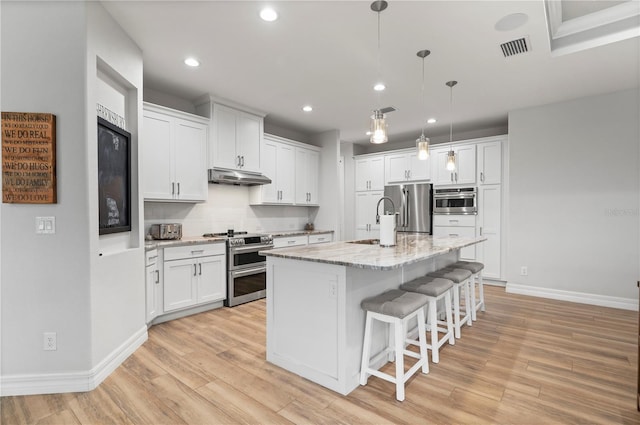 kitchen with white cabinetry, stainless steel appliances, and a kitchen island with sink