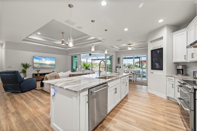 kitchen featuring white cabinetry, sink, a kitchen island with sink, a tray ceiling, and stainless steel appliances