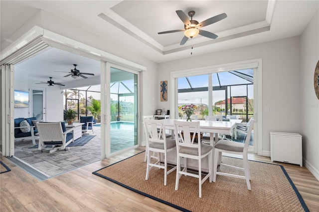 dining space with light hardwood / wood-style floors and a raised ceiling