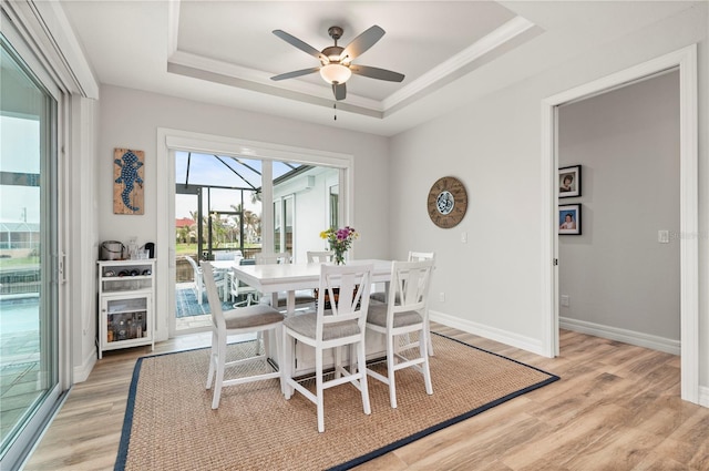 dining room featuring ceiling fan, light hardwood / wood-style floors, and a tray ceiling