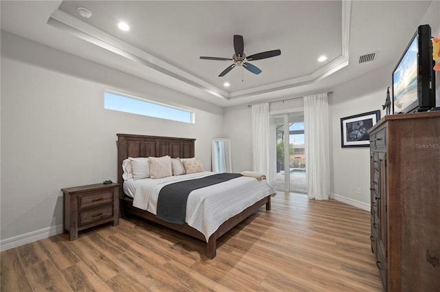 bedroom featuring ceiling fan, a raised ceiling, light hardwood / wood-style floors, and access to outside