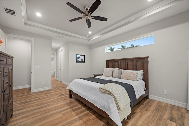 bedroom with a tray ceiling, ceiling fan, and hardwood / wood-style flooring