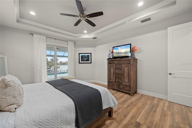 bedroom featuring crown molding, hardwood / wood-style flooring, ceiling fan, access to exterior, and a tray ceiling