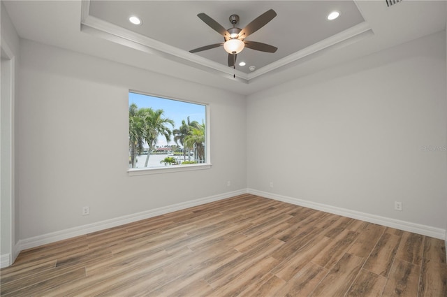 empty room featuring a tray ceiling and light hardwood / wood-style flooring