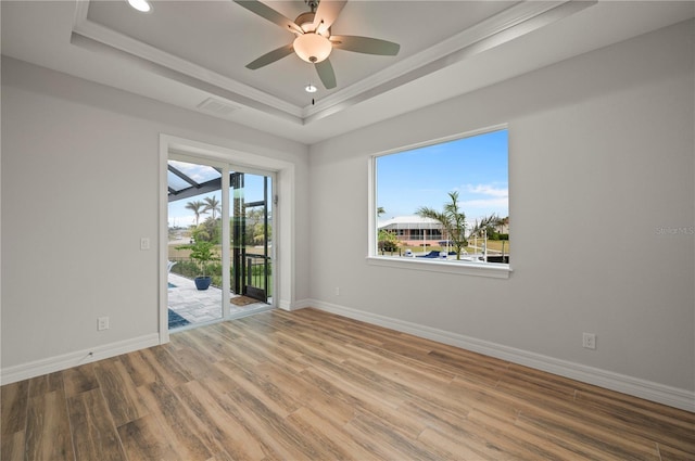 unfurnished room featuring crown molding, wood-type flooring, a raised ceiling, and ceiling fan