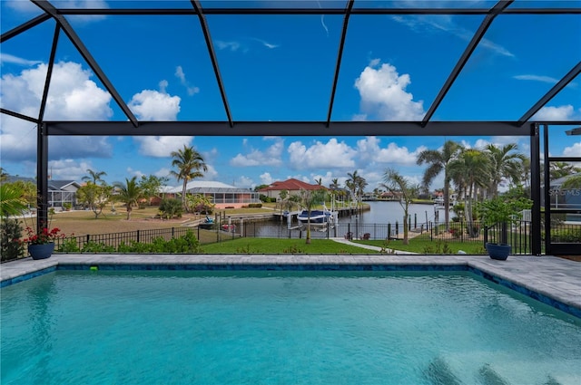 view of pool with a yard, glass enclosure, and a water view