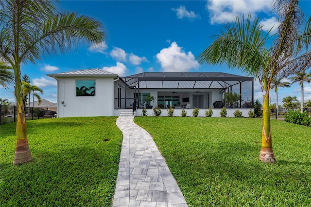 rear view of property with a lanai, a yard, and ceiling fan