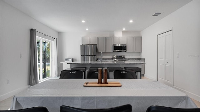 2784 Dode Ave, North Port, FL 34288 - kitchen with appliances with stainless steel finishes, gray cabinetry, an island with sink, a breakfast bar, and recessed lighting