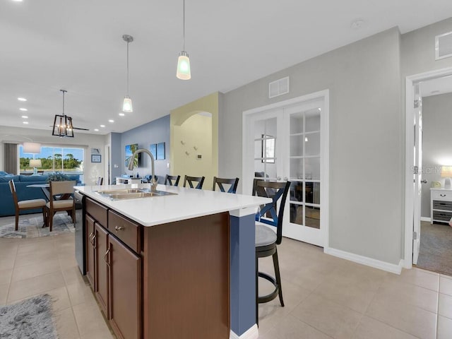 kitchen featuring sink, pendant lighting, a center island with sink, dishwasher, and a breakfast bar area