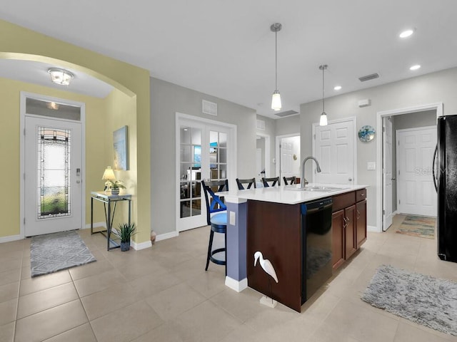 kitchen featuring sink, black appliances, pendant lighting, light tile patterned floors, and a center island with sink